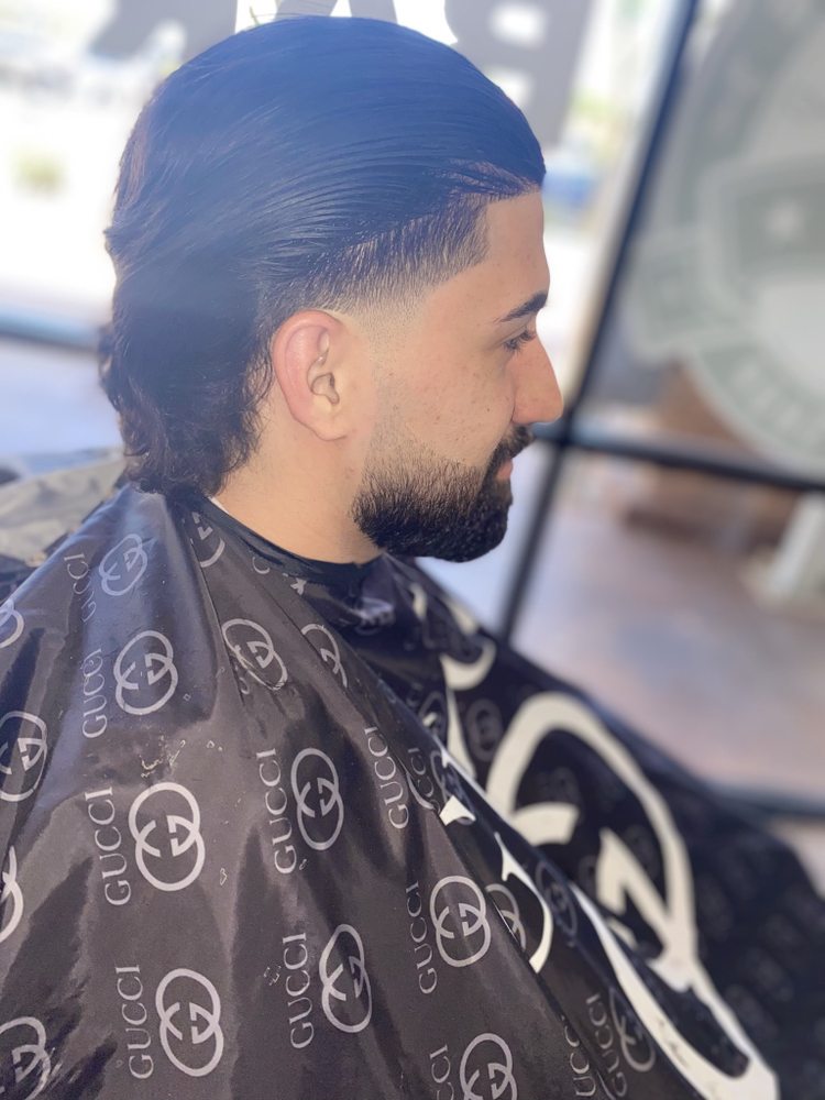 Slicked-back mullet with a mid drop fade cut at Next Level Exclusive Barbershop in Glendale, AZ
