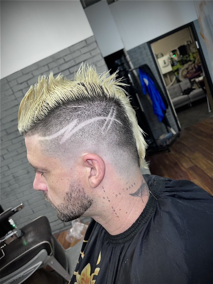 Blonde spiked mohawk with freehand razor hair designs carved into the fade