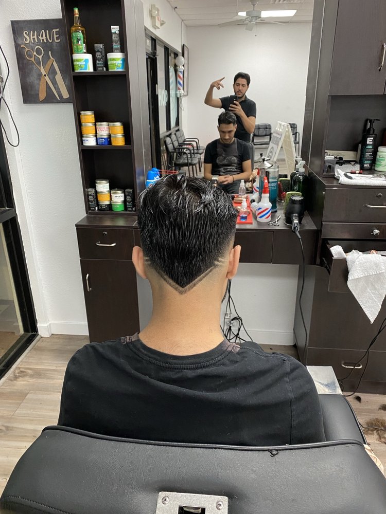 Back view of a V-shaped nape design with a textured comb-over fade in the barber chair