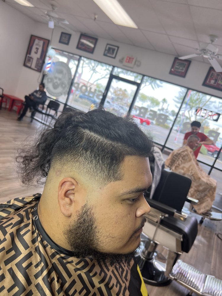 Long curly top with a burst fade and beard blend inside the barbershop
