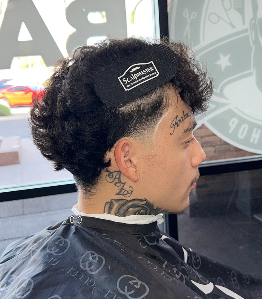 Curly mullet with a low taper fade and sharp line-up at Next Level Exclusive Barbershop in Glendale, AZ